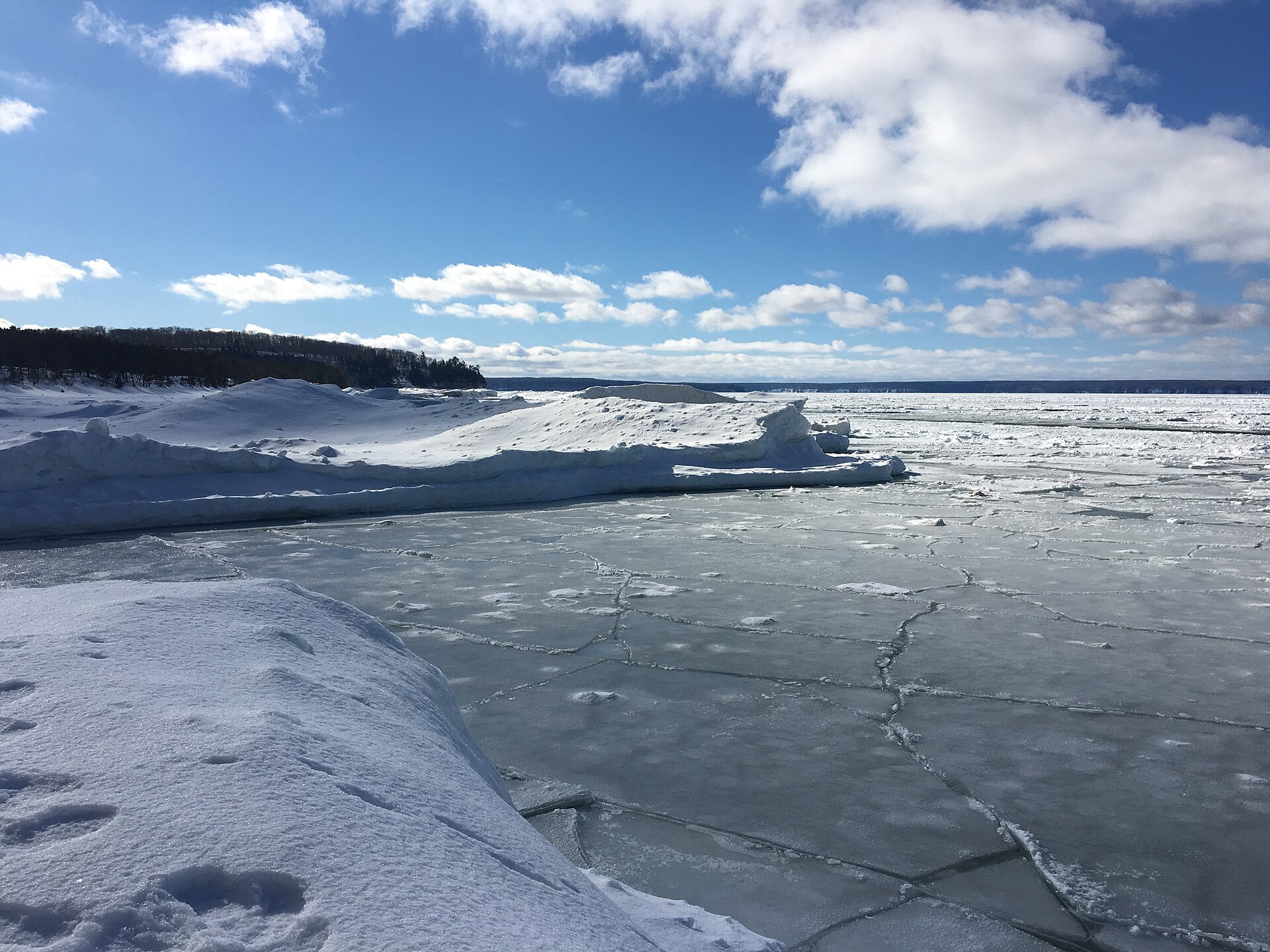 Plate ice and pressure ridges pushed up against a lake shoreline in winter